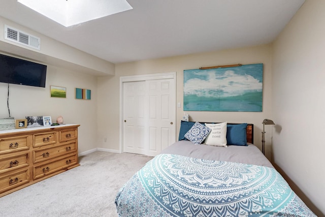 bedroom with visible vents, baseboards, light carpet, a skylight, and a closet