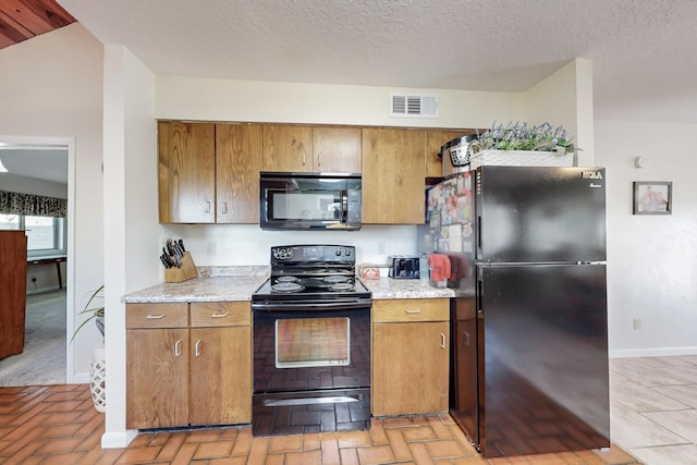 kitchen featuring black appliances, brown cabinetry, visible vents, and baseboards