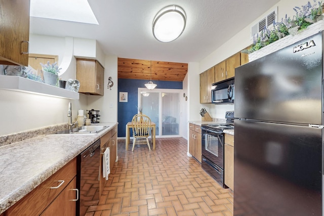 kitchen with a sink, black appliances, a skylight, and light countertops