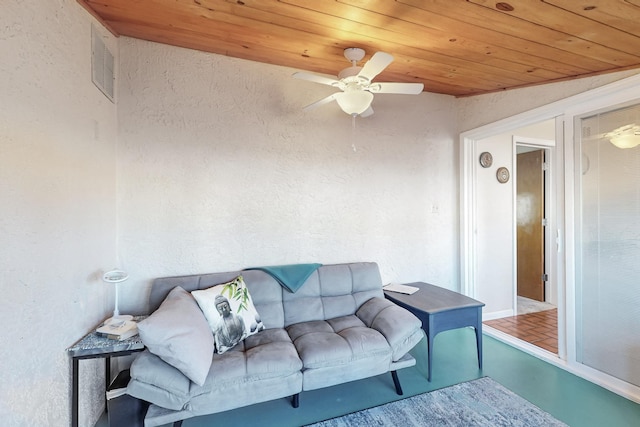 living room with visible vents, wood ceiling, a ceiling fan, and a textured wall