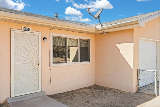 view of exterior entry featuring stucco siding and roof with shingles