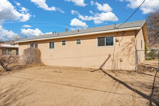 back of house featuring stucco siding and fence