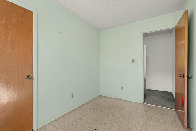 unfurnished bedroom with tile patterned floors, a textured ceiling, and baseboards