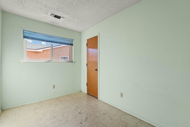 empty room with tile patterned floors, baseboards, visible vents, and a textured ceiling