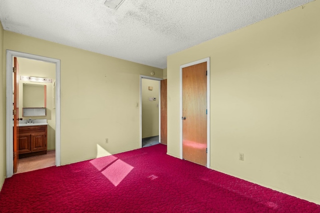 unfurnished bedroom featuring carpet, visible vents, a sink, ensuite bathroom, and a textured ceiling