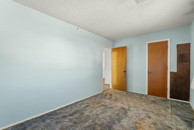 unfurnished bedroom with a textured ceiling, baseboards, and carpet floors