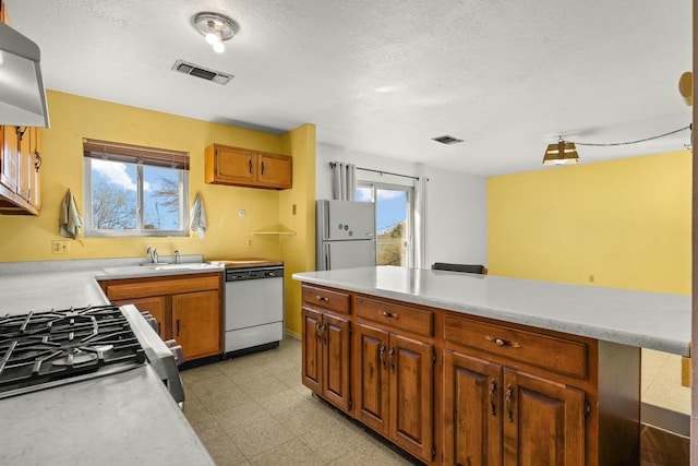 kitchen featuring a sink, visible vents, white appliances, and light countertops