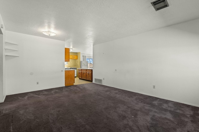 unfurnished living room with visible vents, light colored carpet, and a textured ceiling