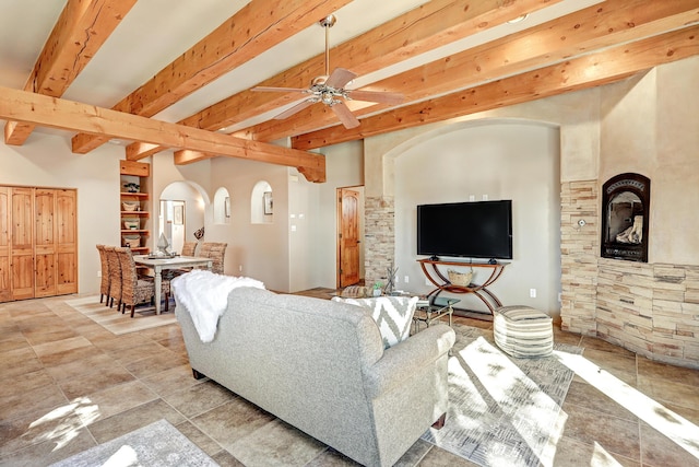 living area with arched walkways, beamed ceiling, and ceiling fan