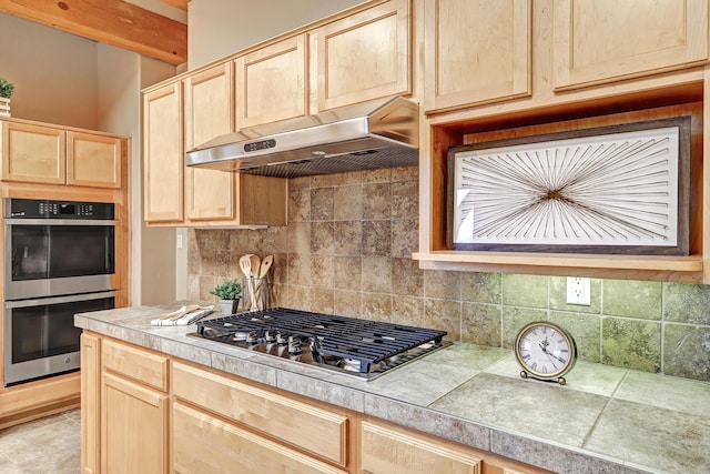 kitchen with backsplash, appliances with stainless steel finishes, light brown cabinets, and under cabinet range hood