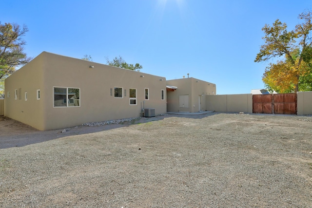 back of property with central air condition unit, fence, and stucco siding