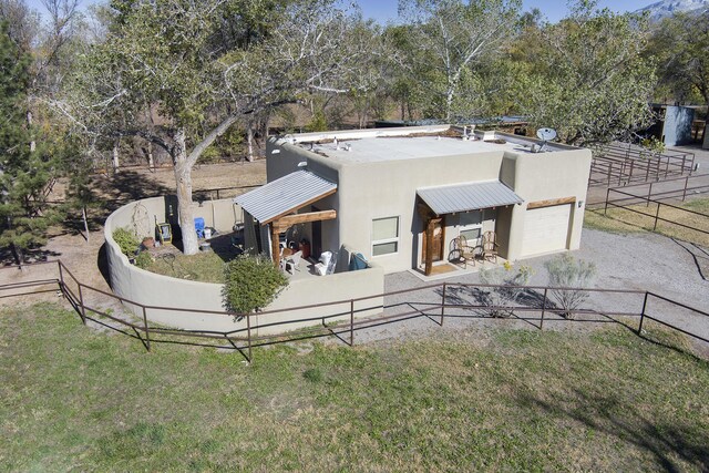 view of front of home with stucco siding, metal roof, a front lawn, and fence