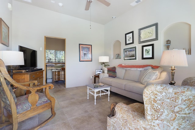 living area featuring a ceiling fan, visible vents, a high ceiling, arched walkways, and tile patterned flooring