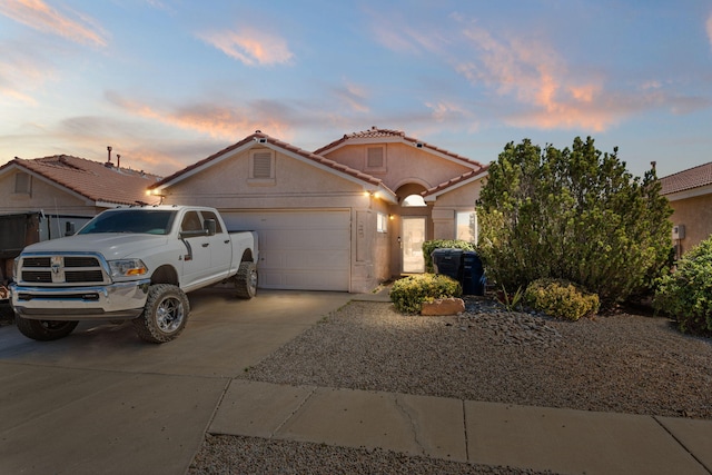 view of front of property with stucco siding, a garage, driveway, and a tile roof