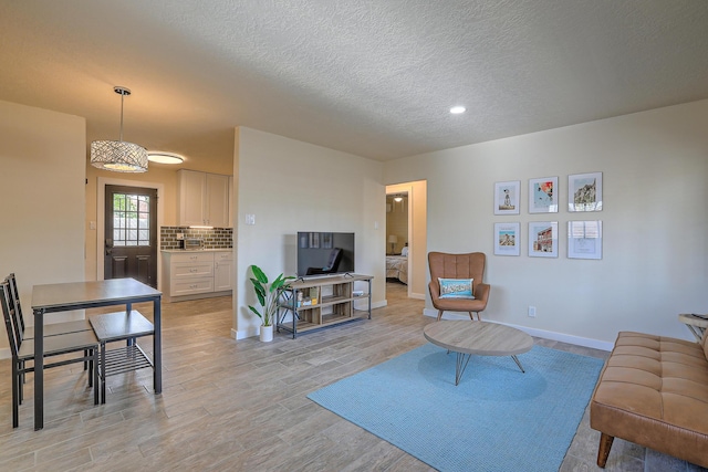 living room with baseboards, light wood-type flooring, and a textured ceiling