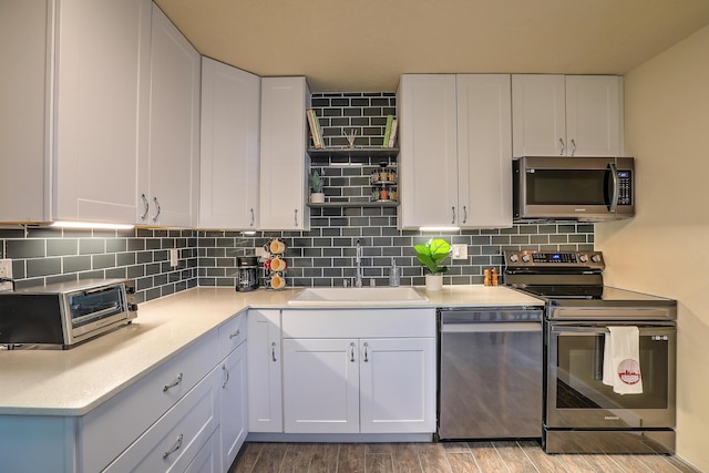 kitchen featuring a sink, backsplash, appliances with stainless steel finishes, and white cabinetry