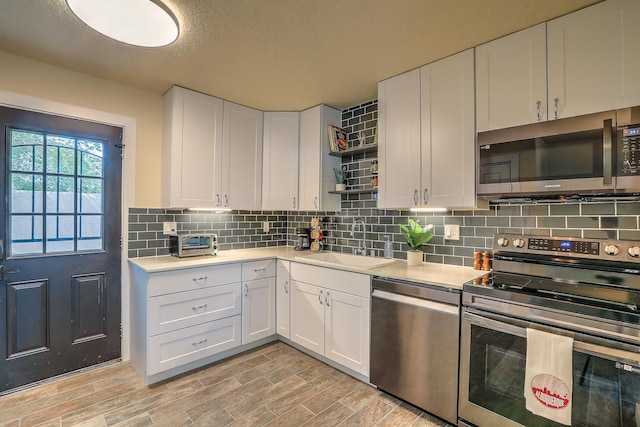 kitchen with a sink, stainless steel appliances, tasteful backsplash, and light countertops