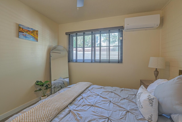 bedroom with a wall unit AC, baseboards, and ceiling fan