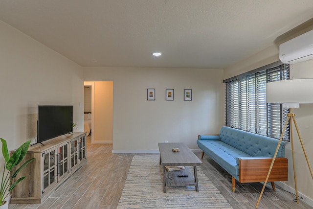 living room with a wall unit AC, baseboards, and wood finished floors