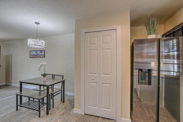 dining room featuring a textured ceiling, baseboards, and wood finish floors