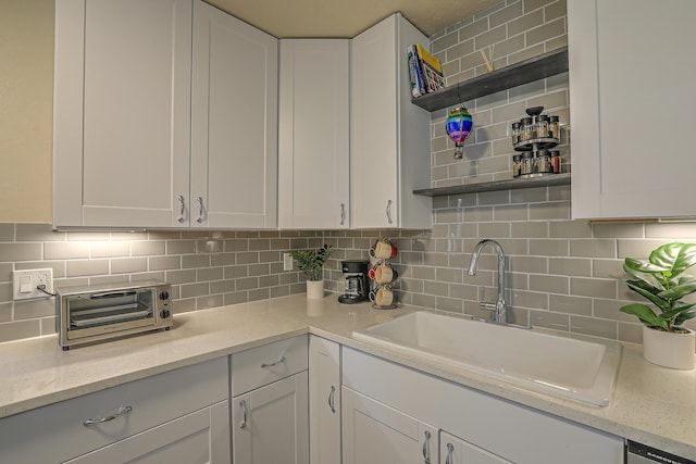 kitchen featuring tasteful backsplash, white cabinets, open shelves, and a sink