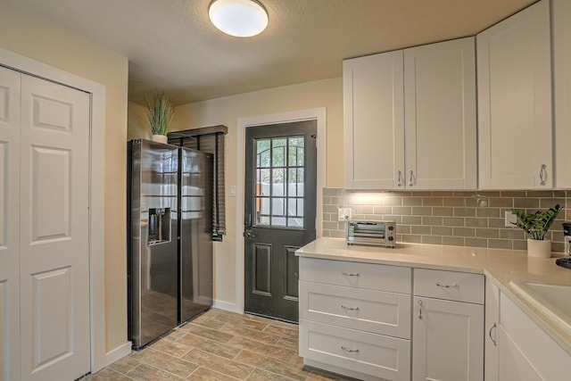 kitchen with decorative backsplash, white cabinets, and stainless steel fridge with ice dispenser