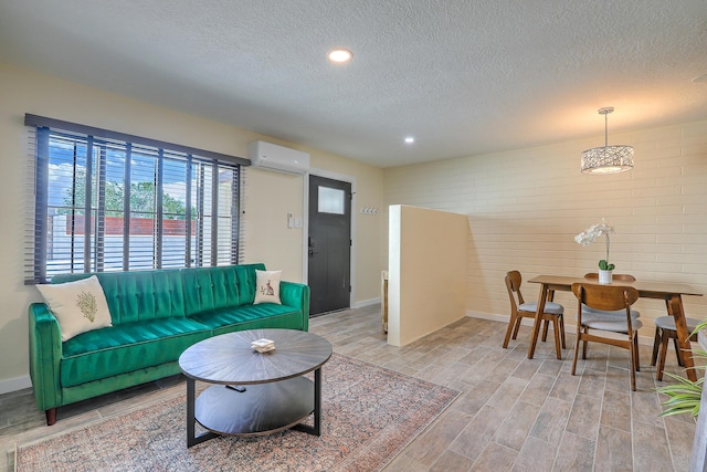 living room featuring a textured ceiling, a wall unit AC, baseboards, and wood tiled floor