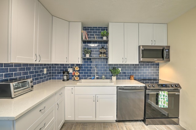 kitchen featuring a sink, stainless steel appliances, light wood-style flooring, and white cabinetry