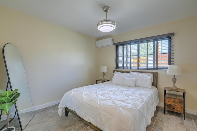 bedroom featuring baseboards, an AC wall unit, and wood finished floors