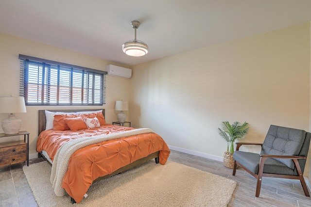 bedroom featuring wood finished floors, baseboards, and a wall mounted air conditioner