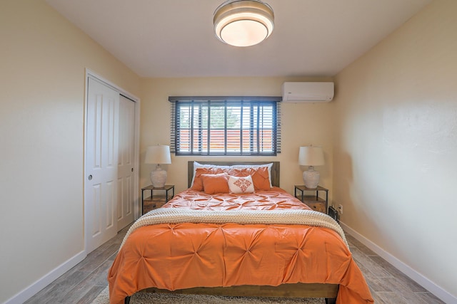 bedroom with a closet, a wall mounted air conditioner, baseboards, and wood tiled floor