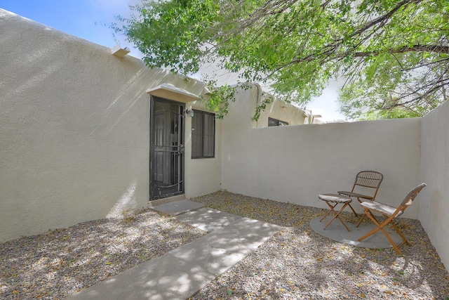 doorway to property featuring stucco siding and fence