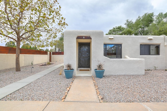 view of front of house featuring stucco siding and fence