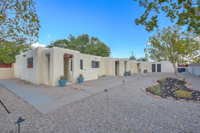 pueblo-style house featuring stucco siding and fence