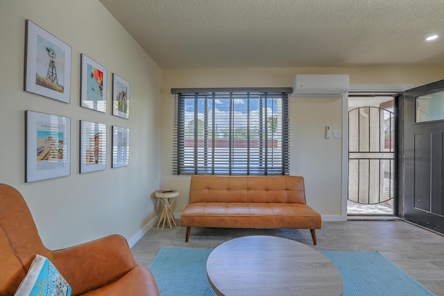 sitting room with a textured ceiling, an AC wall unit, and baseboards