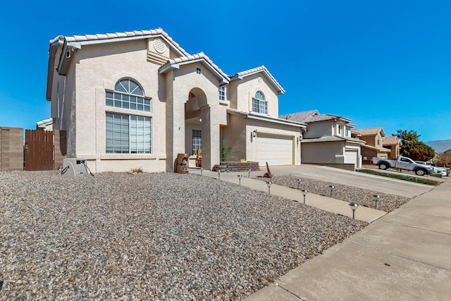 view of front facade with stucco siding, an attached garage, driveway, and fence