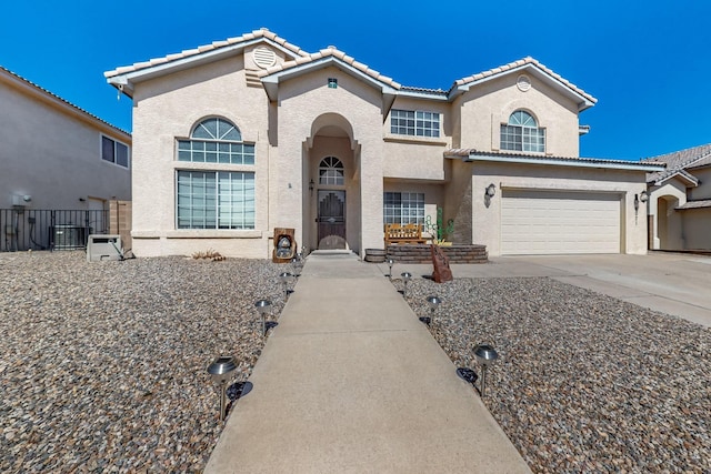 mediterranean / spanish home with concrete driveway, an attached garage, central AC unit, and stucco siding