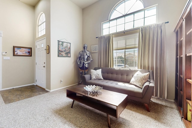 living room featuring carpet flooring, baseboards, and a towering ceiling