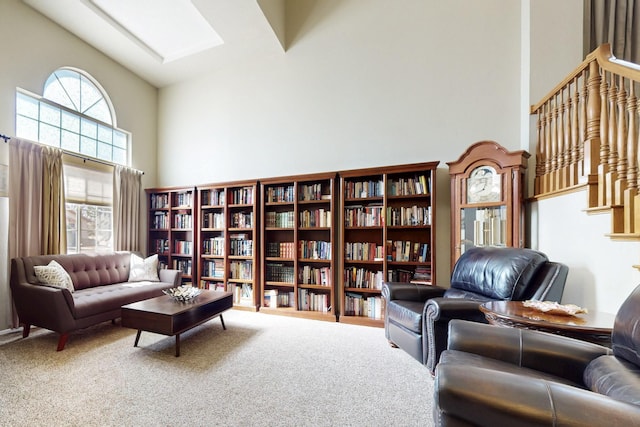 living area with a skylight, carpet, and high vaulted ceiling