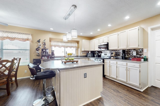 kitchen with a center island, dark wood-type flooring, decorative backsplash, stainless steel appliances, and white cabinetry