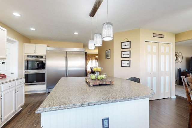 kitchen featuring stainless steel appliances, a kitchen island, white cabinets, and dark wood finished floors