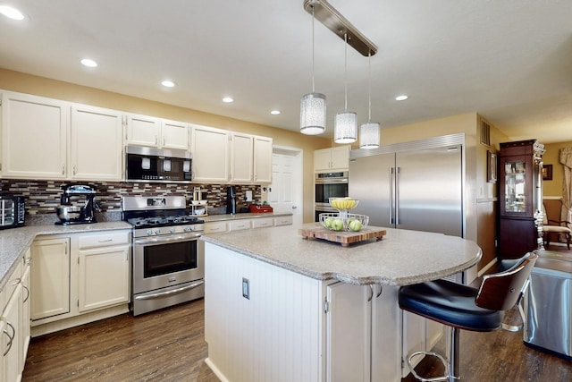 kitchen with tasteful backsplash, appliances with stainless steel finishes, dark wood finished floors, and a center island