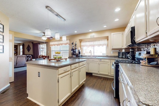 kitchen featuring visible vents, a center island, dark wood finished floors, gas range, and a sink