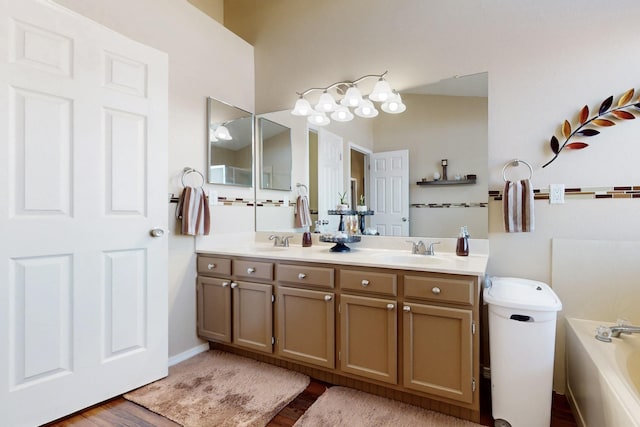 bathroom with a sink, wood finished floors, double vanity, and a washtub