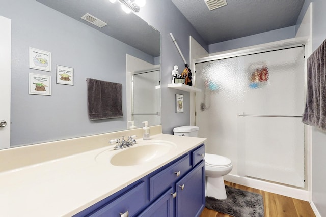 bathroom with visible vents, wood finished floors, toilet, and a stall shower