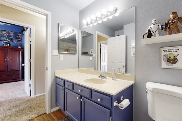 bathroom with toilet, vanity, and baseboards