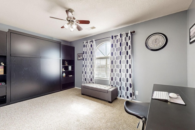 carpeted office space featuring ceiling fan, visible vents, and a textured ceiling