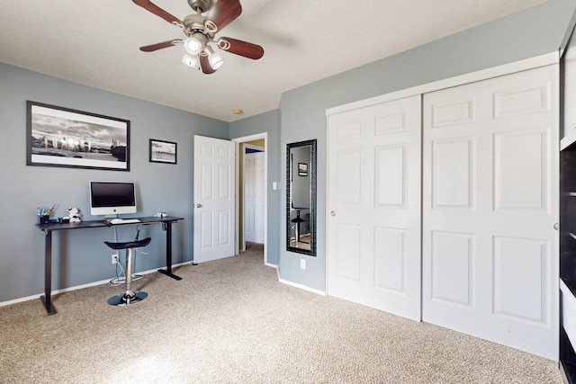 carpeted office space featuring baseboards and a ceiling fan