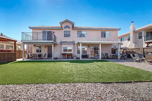 rear view of property featuring stucco siding, a patio, a balcony, and a fenced backyard