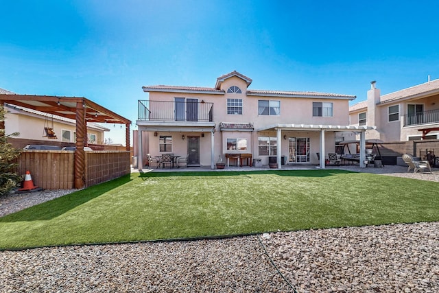 back of house featuring stucco siding, a yard, a balcony, a patio area, and a pergola